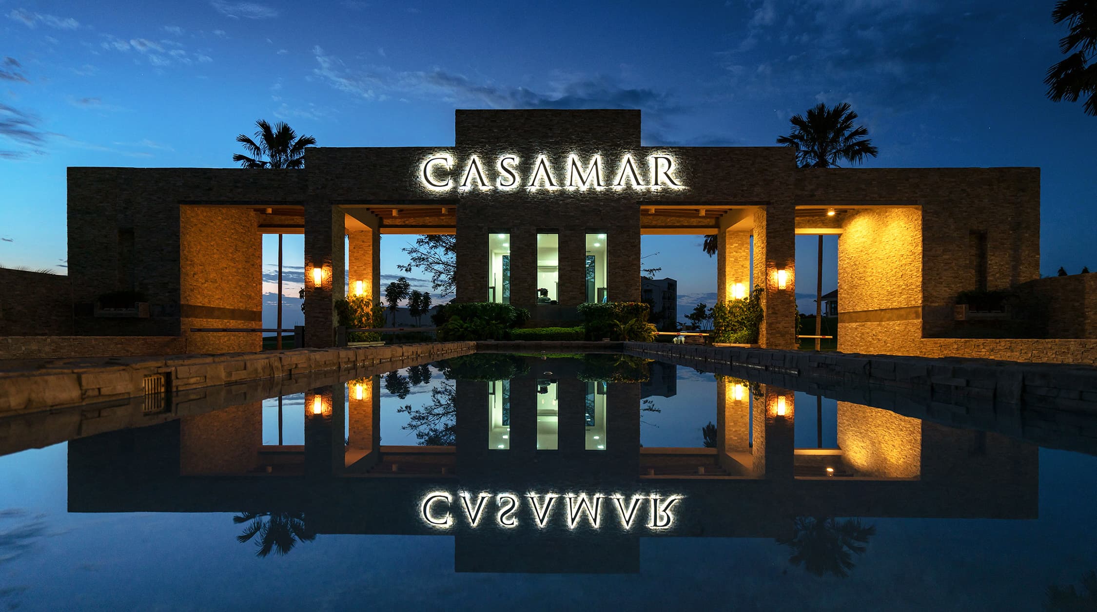 Illuminated Casamar entrance reflected in the water at dusk, Ocean Villas community
