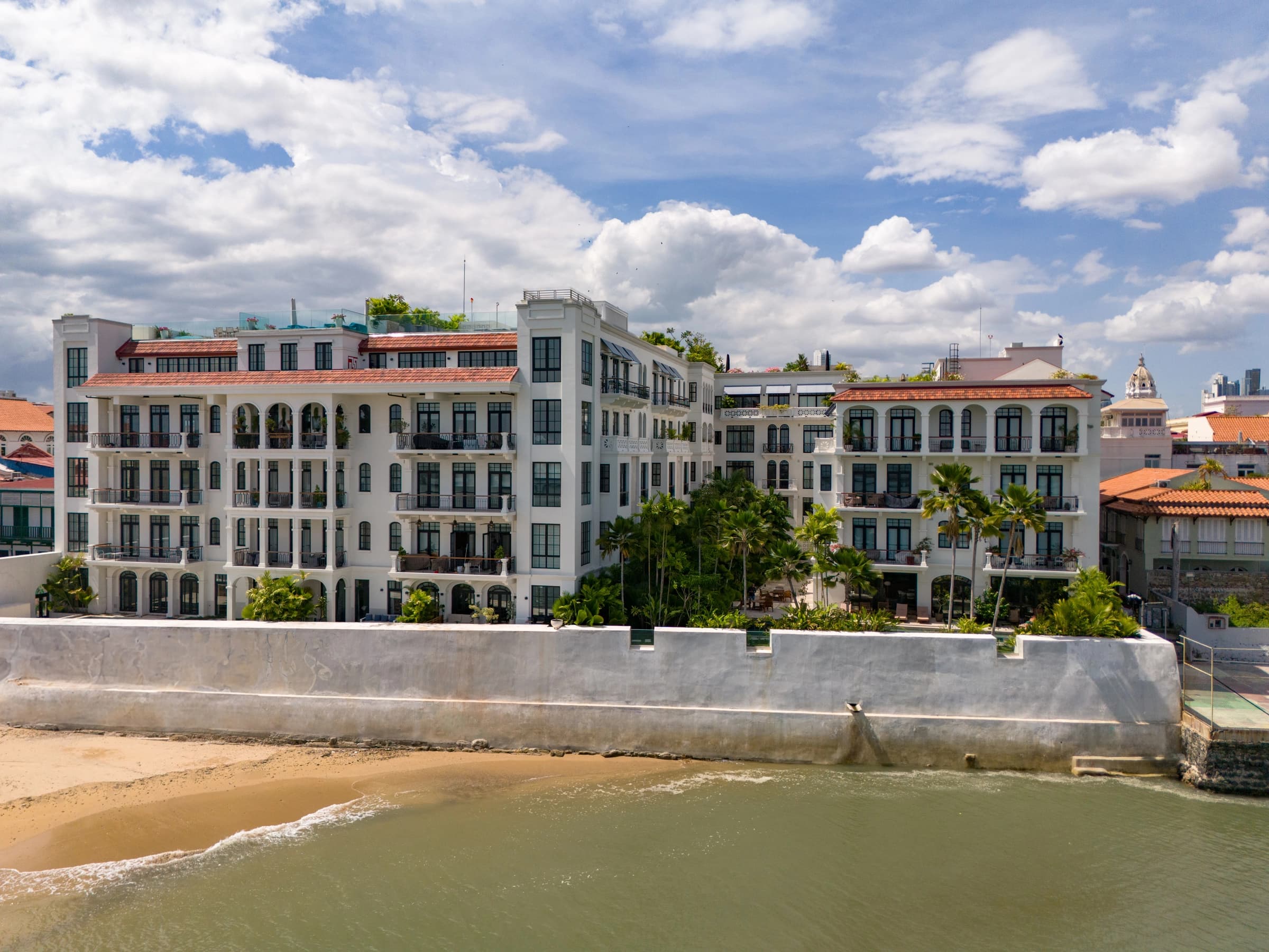 Santa Familia condominium, white neoclassical buildings with red-tile roofs behind the seawall on Playa Santo Domingo, Casco Viejo
