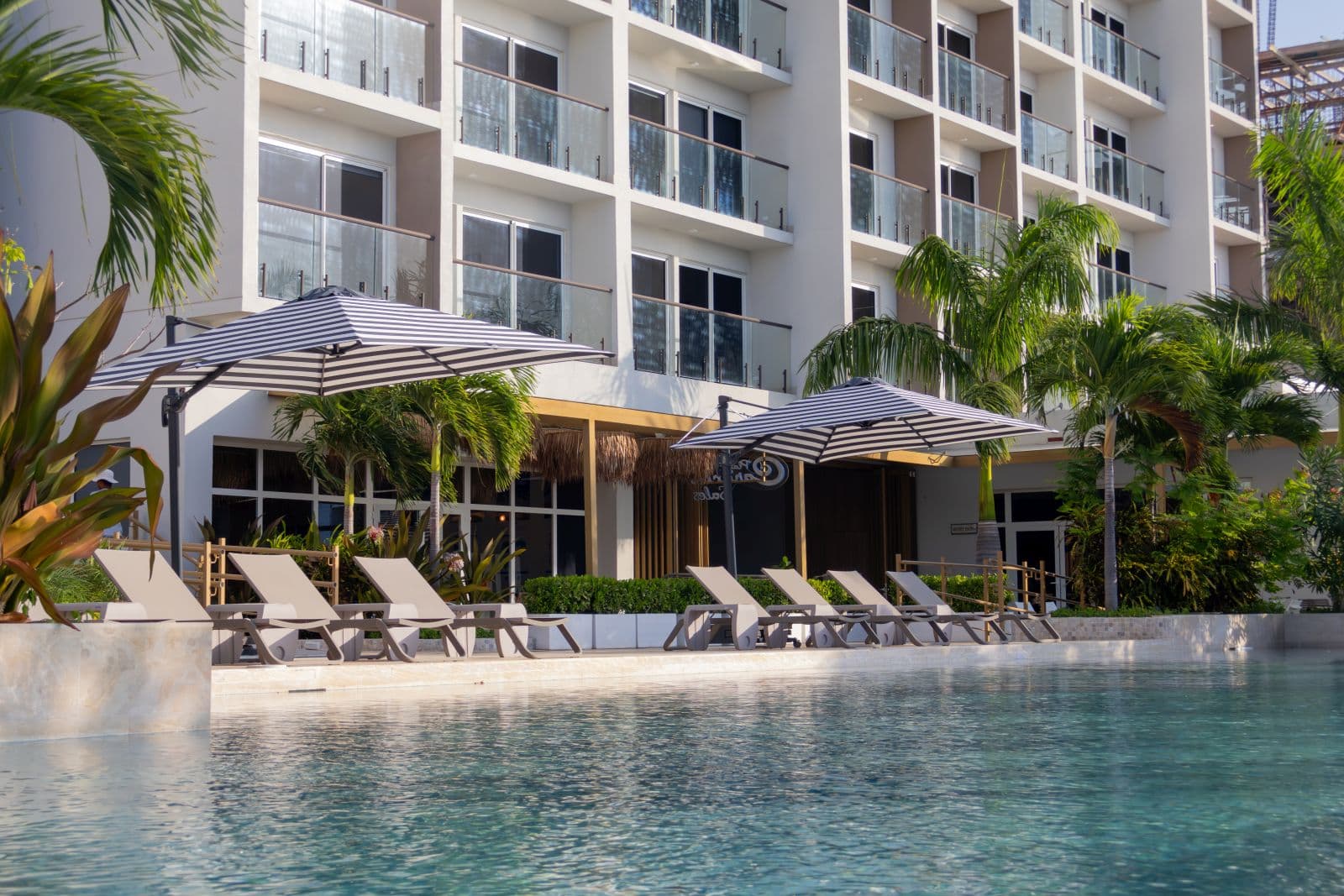 Pool deck with lounge chairs below a Playa Caracol apartment building