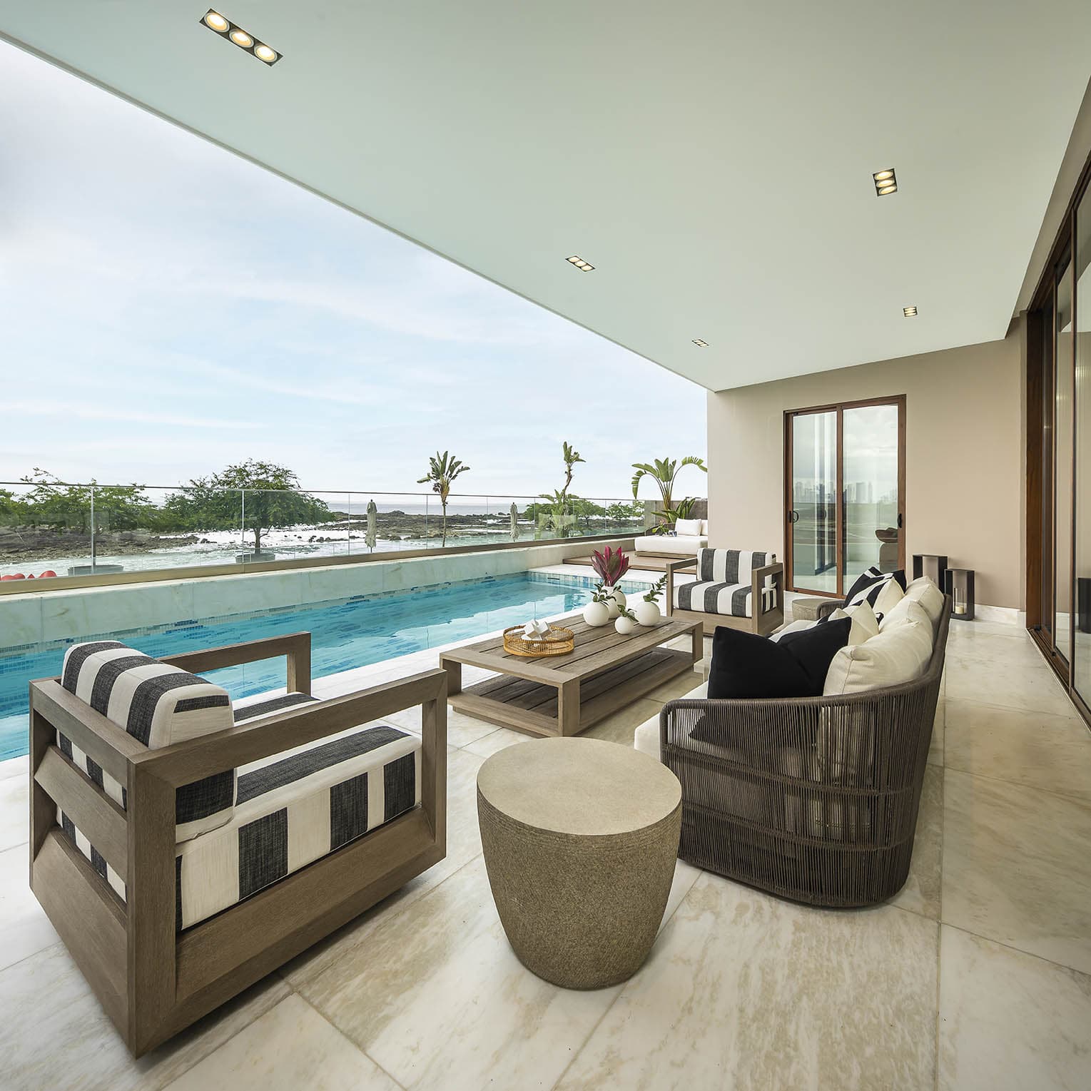 Covered terrace with lounge chairs overlooking the pool at The Residences