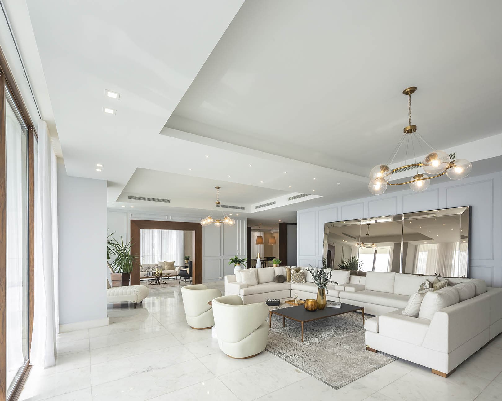 Open living room with white sofas and a chandelier at The Residences
