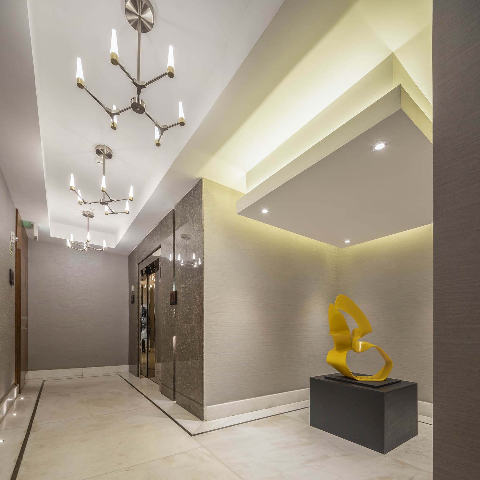 Elevator lobby with chandeliers and a sculpture at The Residences