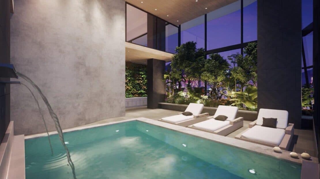 Indoor pool with a water jet and loungers at Victory Sport