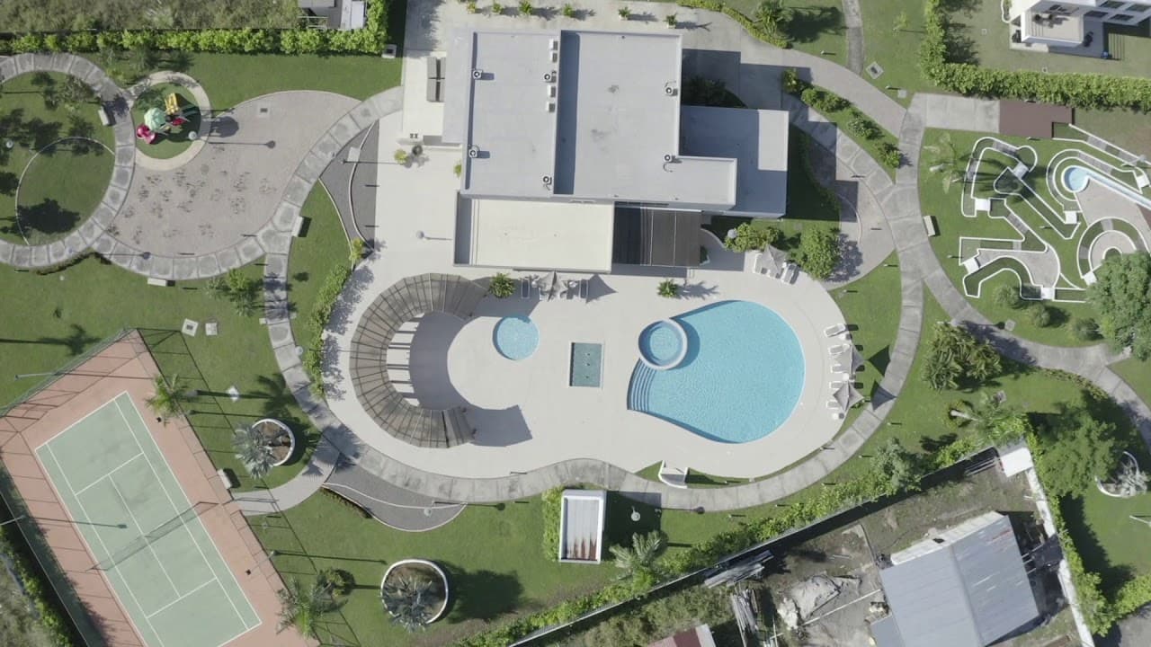 Aerial view of the Villasur Residences clubhouse with swimming pool, tennis court and landscaped paths in Costa Sur