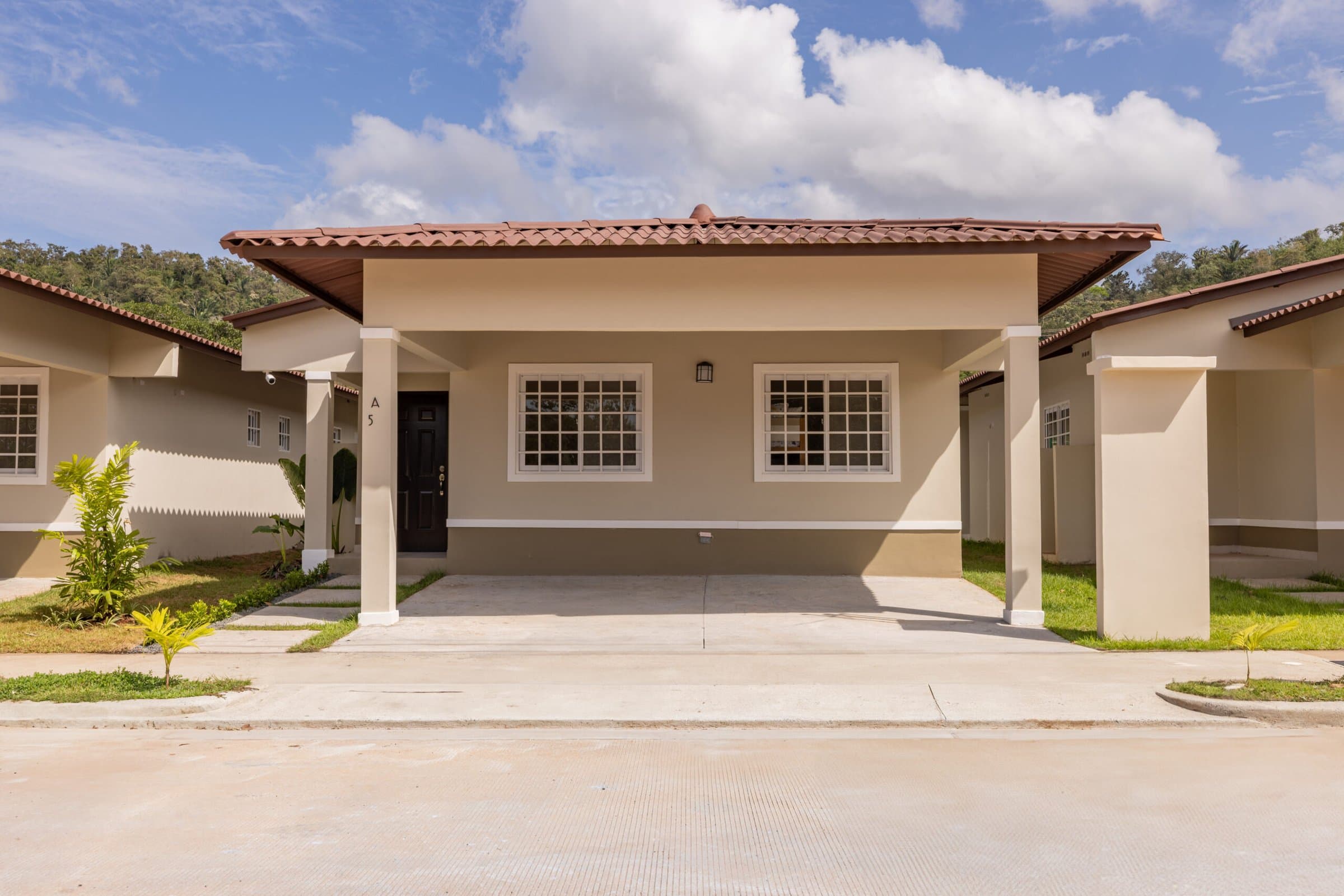 Front of a finished single-storey house with covered carport at Colonia Real in Capira