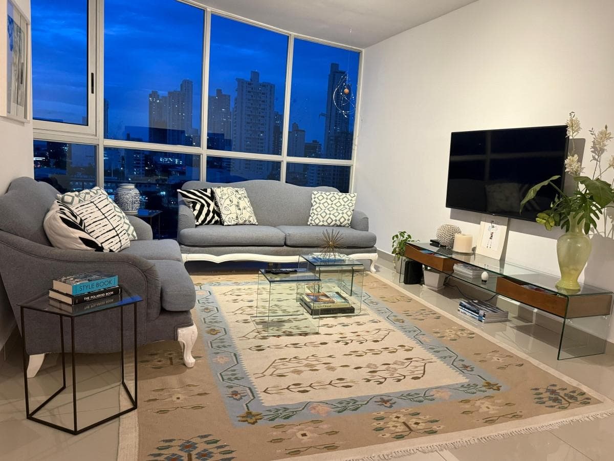 Living room with blue-tinted floor-to-ceiling windows in an apartment at PH Joy Tower, San Francisco, Panama City