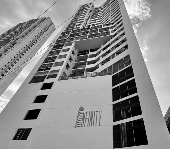 Black-and-white upward view of the PH Infinity residential tower facade with its name sign, San Francisco, Panama City
