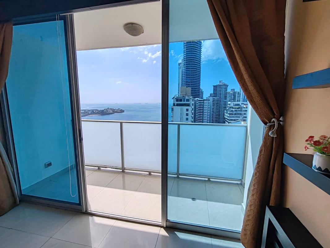 Glass balcony door opening onto sea and Paitilla tower views at PH Pacific Sky, Panama City