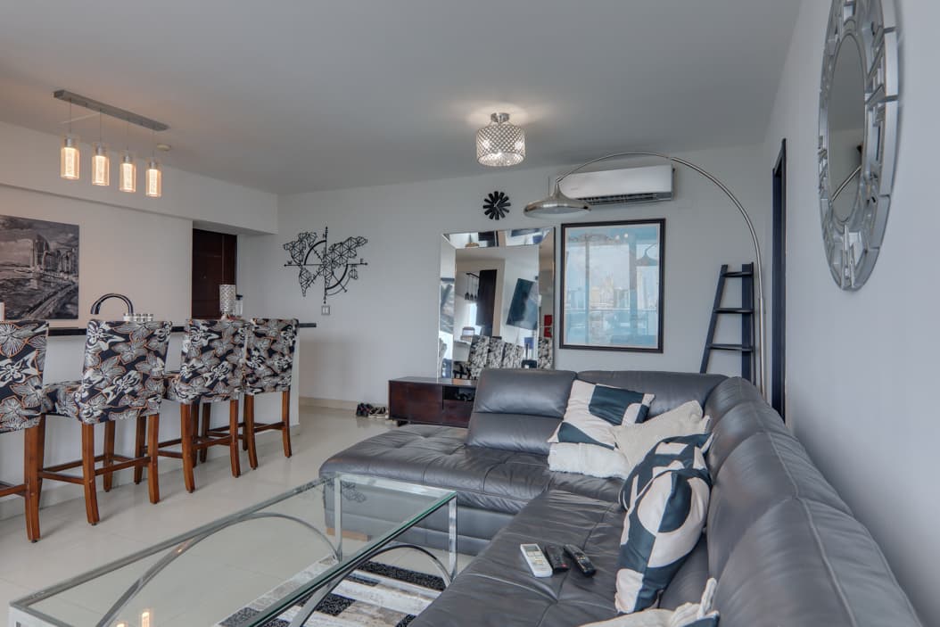Living room with a gray sectional and breakfast bar in an apartment at Harmony Tower, San Francisco, Panama City