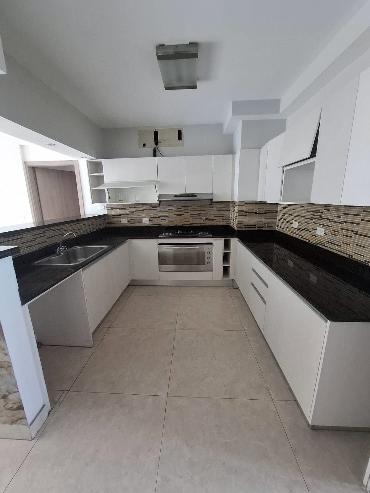 Kitchen with dark granite counters and white cabinets in an apartment at Harmony Tower, San Francisco, Panama City