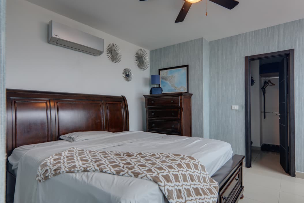 Furnished bedroom with a sleigh bed and walk-in closet in an apartment at Harmony Tower, San Francisco, Panama City