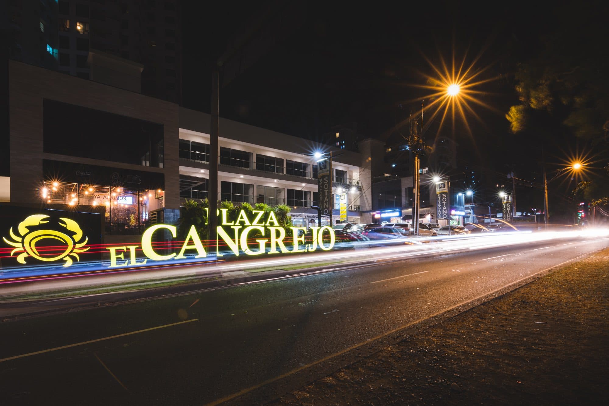 Illuminated Plaza El Cangrejo sign on the avenue at night