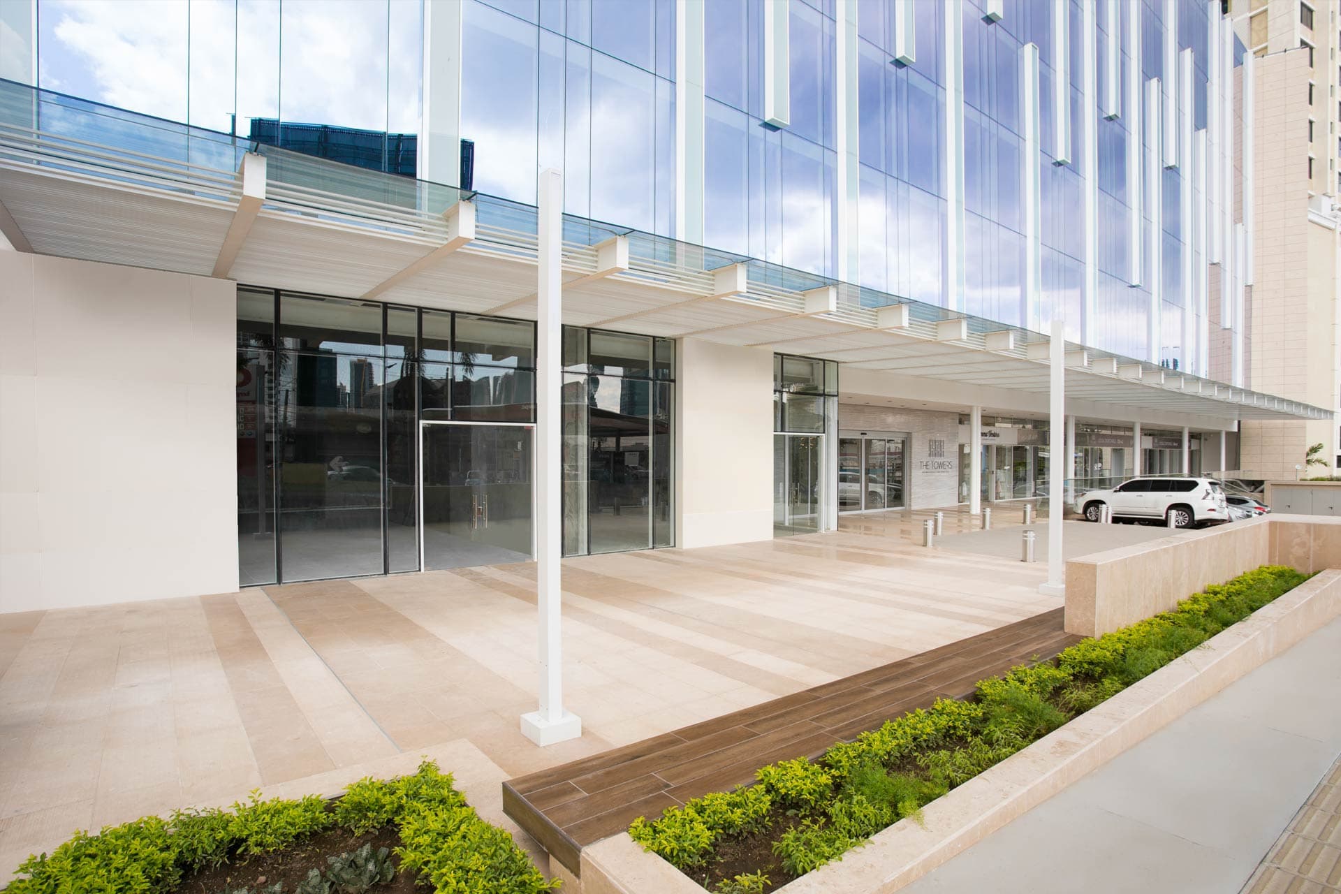 Entrance plaza with planters and glass storefronts at The Towers Business Plaza
