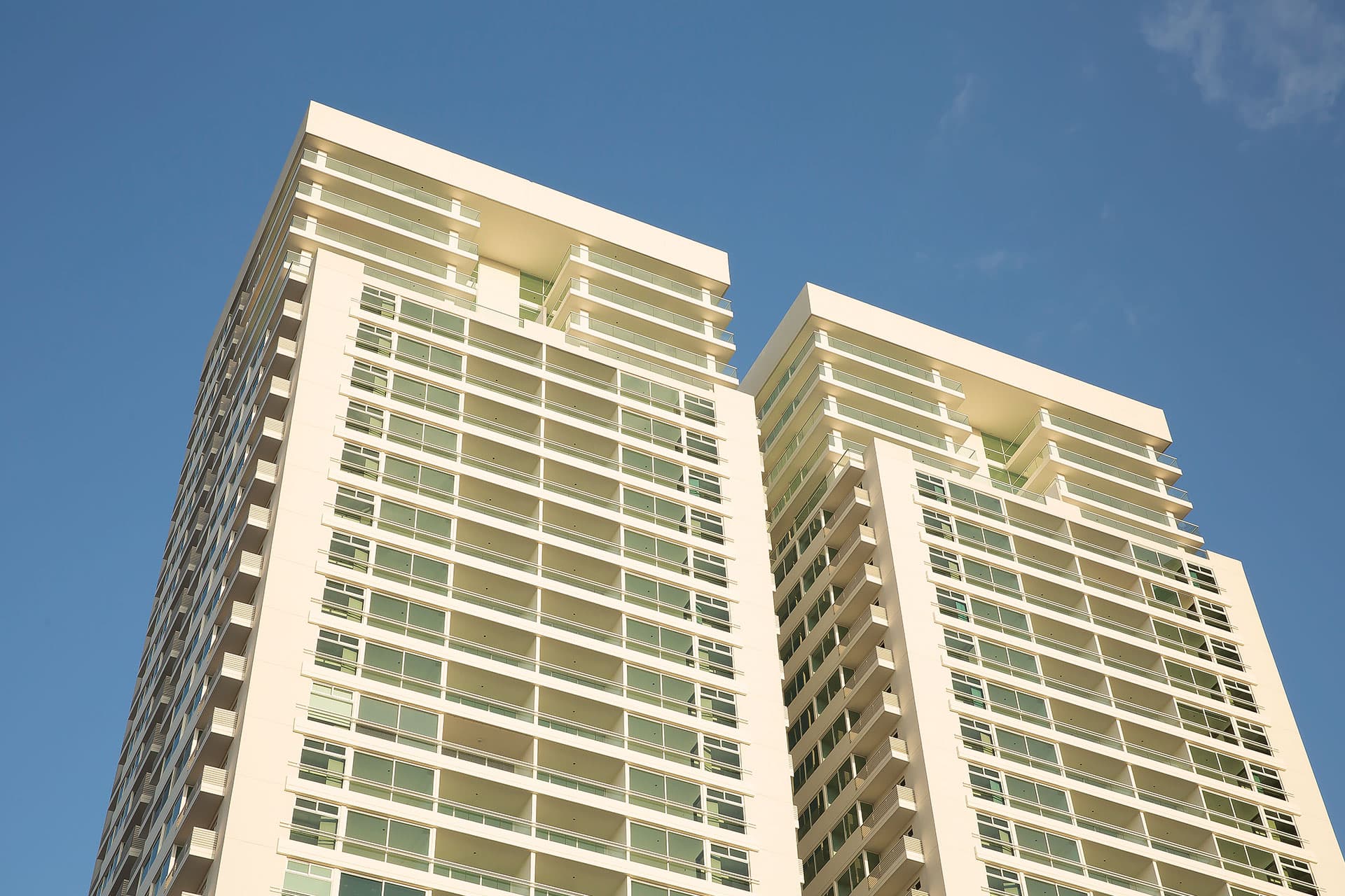 Upper floors and glass balconies of The Towers Residences against a blue sky in San Francisco, Panama City