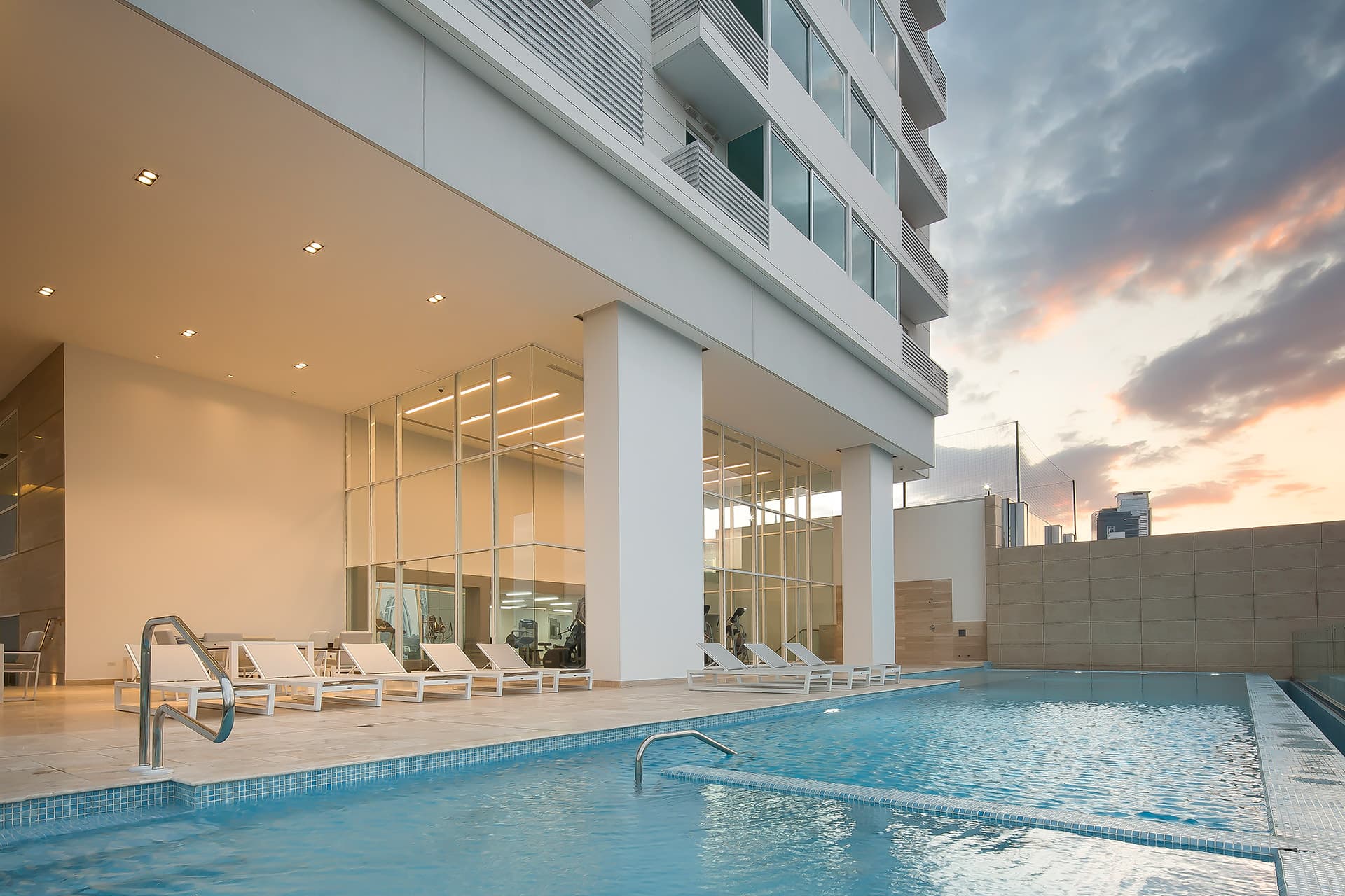 Pool deck with sun loungers beneath the tower at The Towers Residences