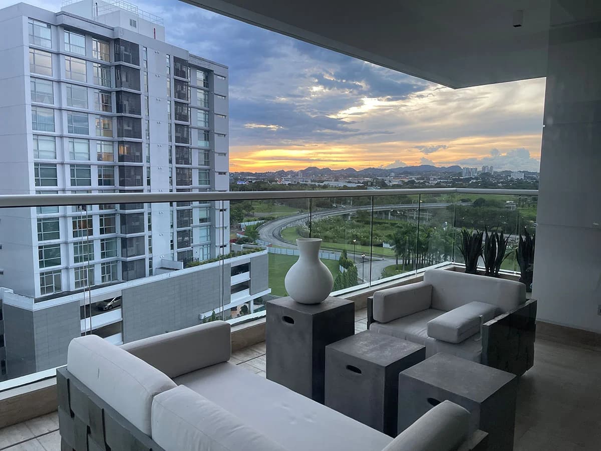 Covered terrace with outdoor sofas and a sunset view over Costa del Este at Marea II