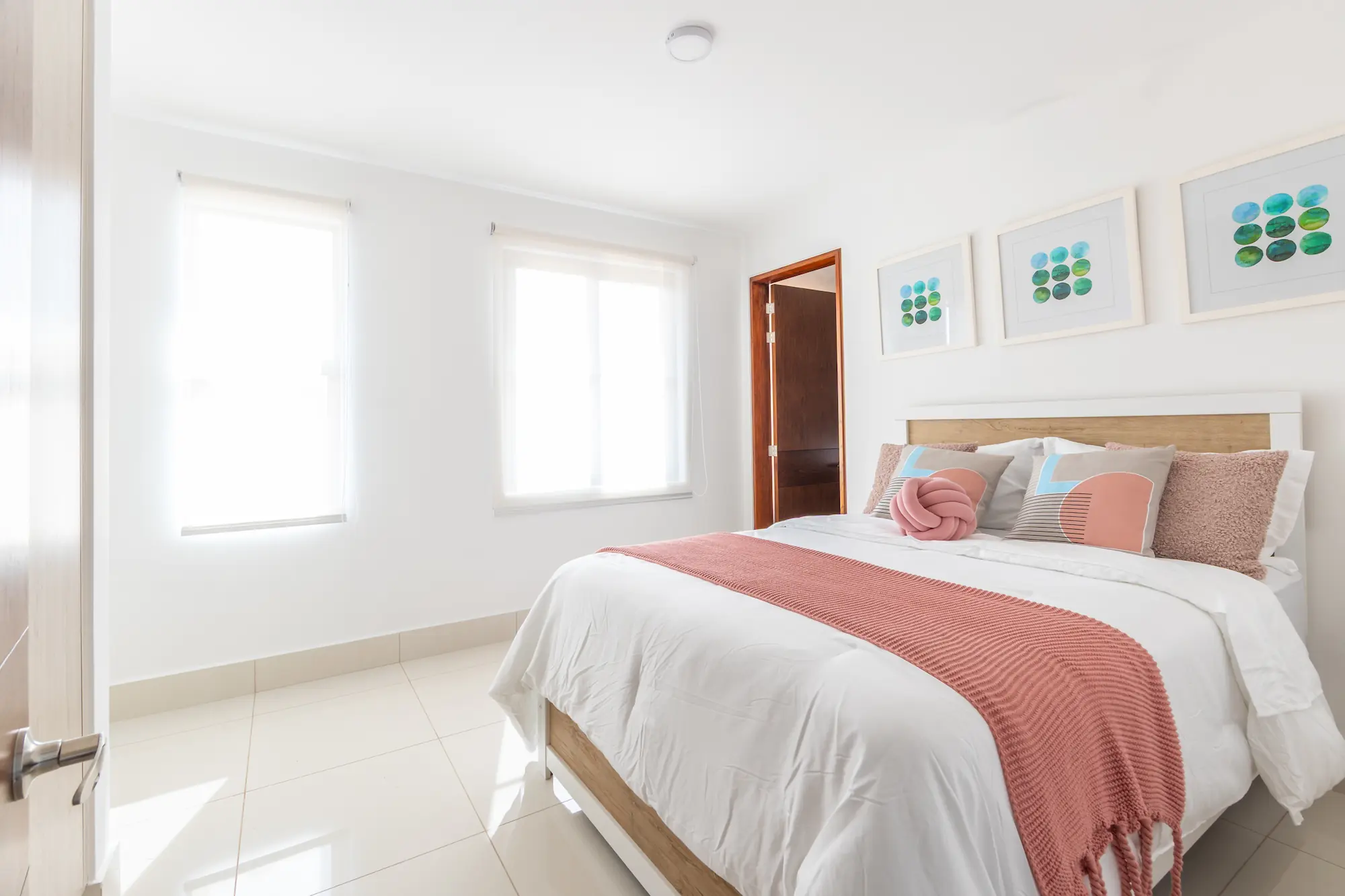 Bedroom with coral bedding and twin windows in an Arcadia model house, Costa Verde