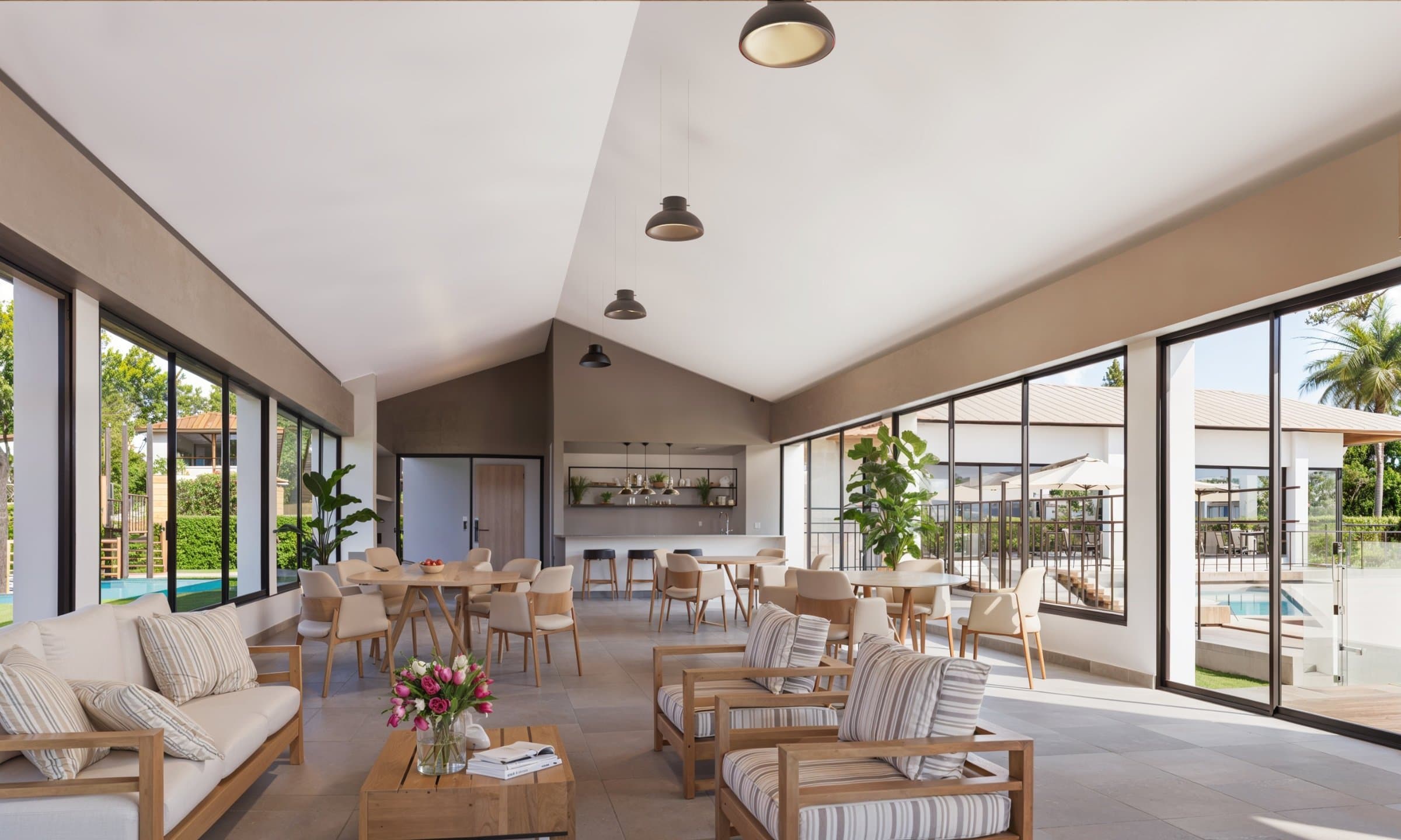 Open clubhouse lounge with dining tables and pool view at Alborada