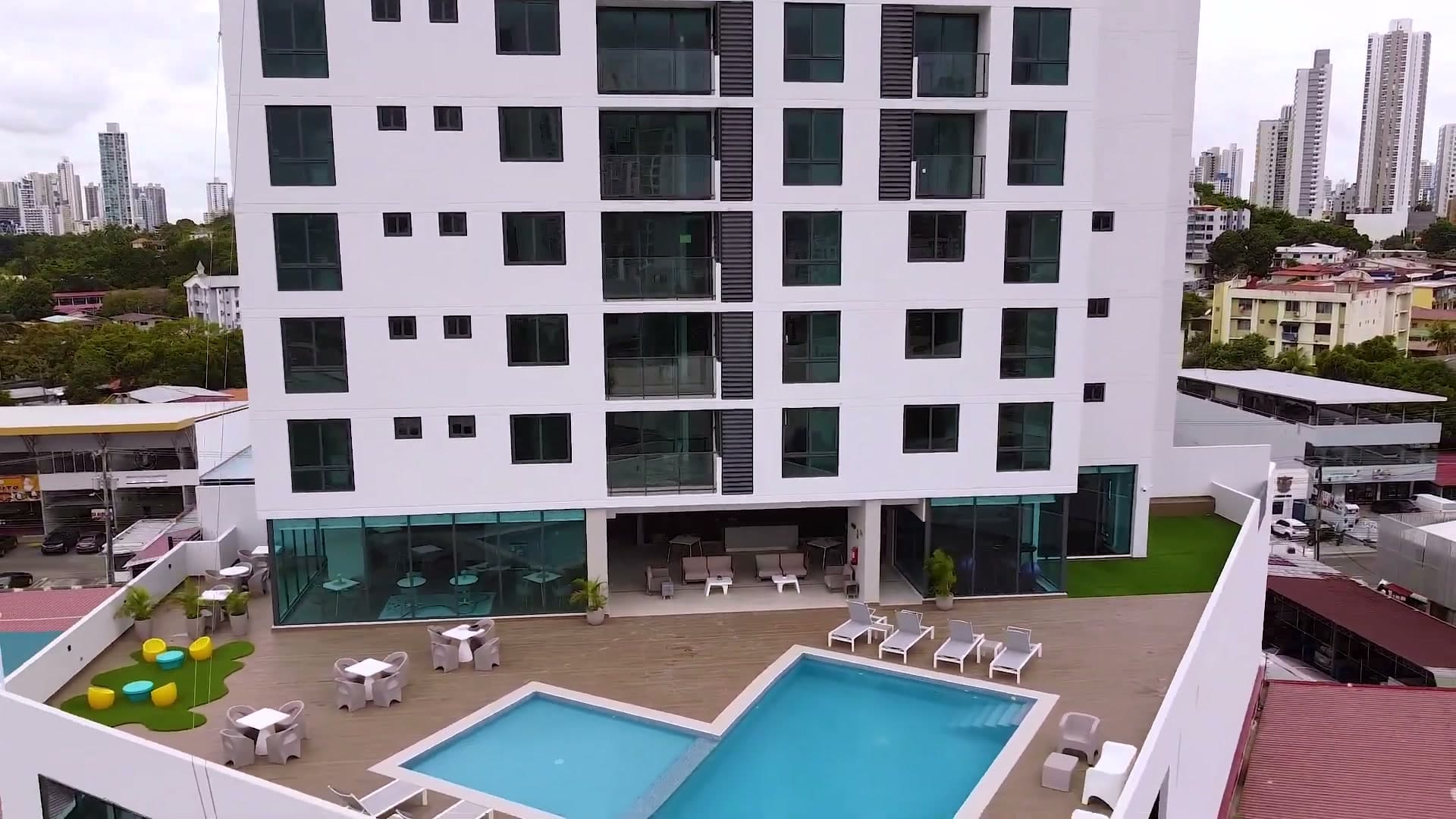 Aerial view of Época Parque Lefevre with its pool terrace and the Panama City skyline behind