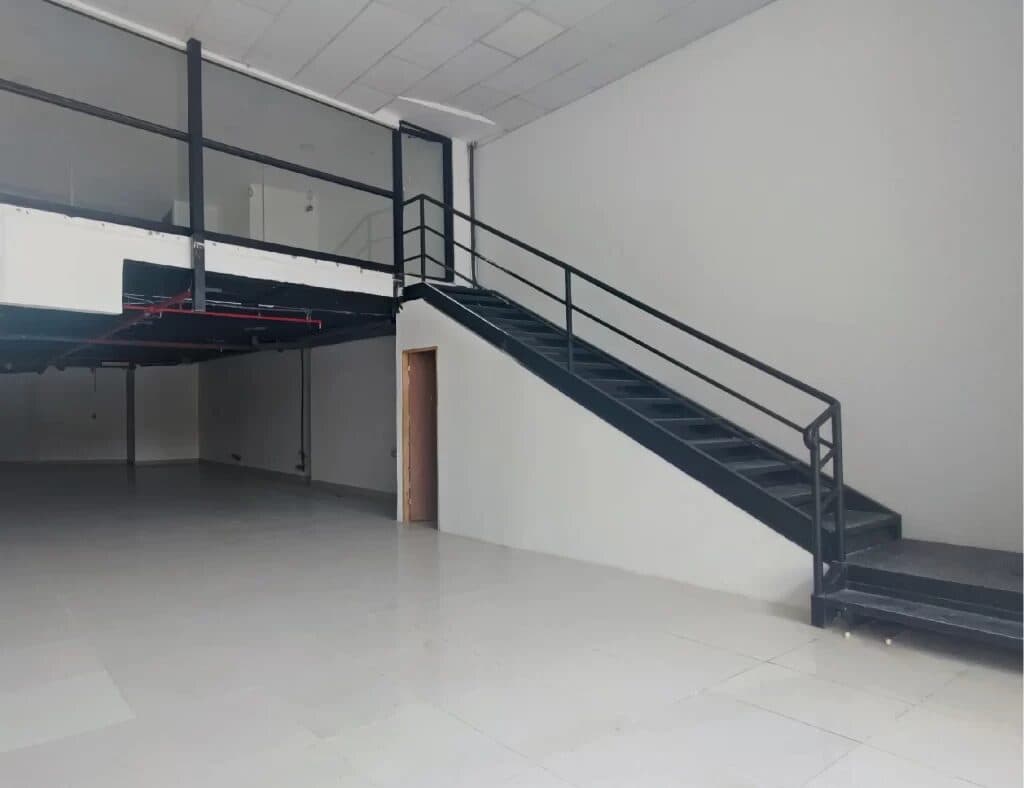 Empty double-height commercial unit with a steel staircase to the mezzanine at Allure at the Park