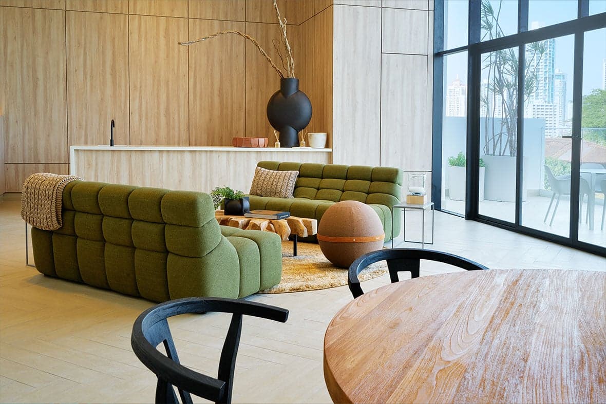 Residents' lounge with green sofas and floor-to-ceiling windows at Victory Wellness