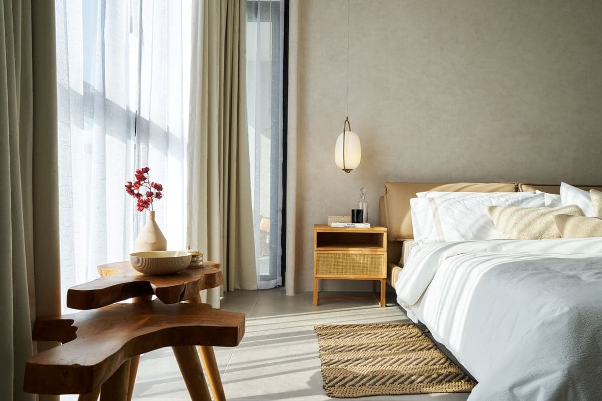 Bedroom with sheer curtains and a wooden side table in a Victory Wellness apartment