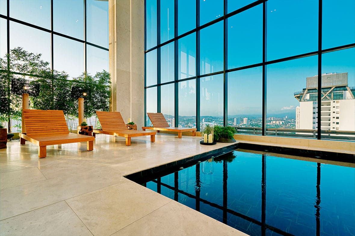 Glass-walled wellness pool with wooden loungers at Victory Wellness