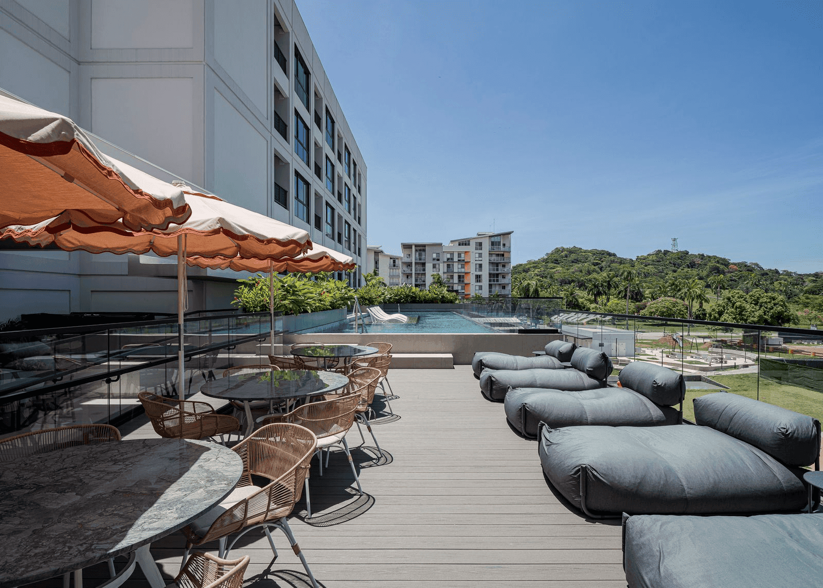 Sun deck with loungers beside the pool at Cëntriqo, with green hills behind
