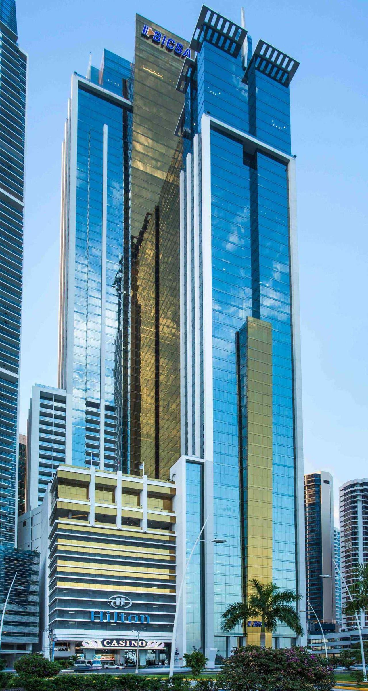 BICSA Financial Center glass tower with its blue and gold facade and the Hilton podium on Avenida Balboa, Panama City