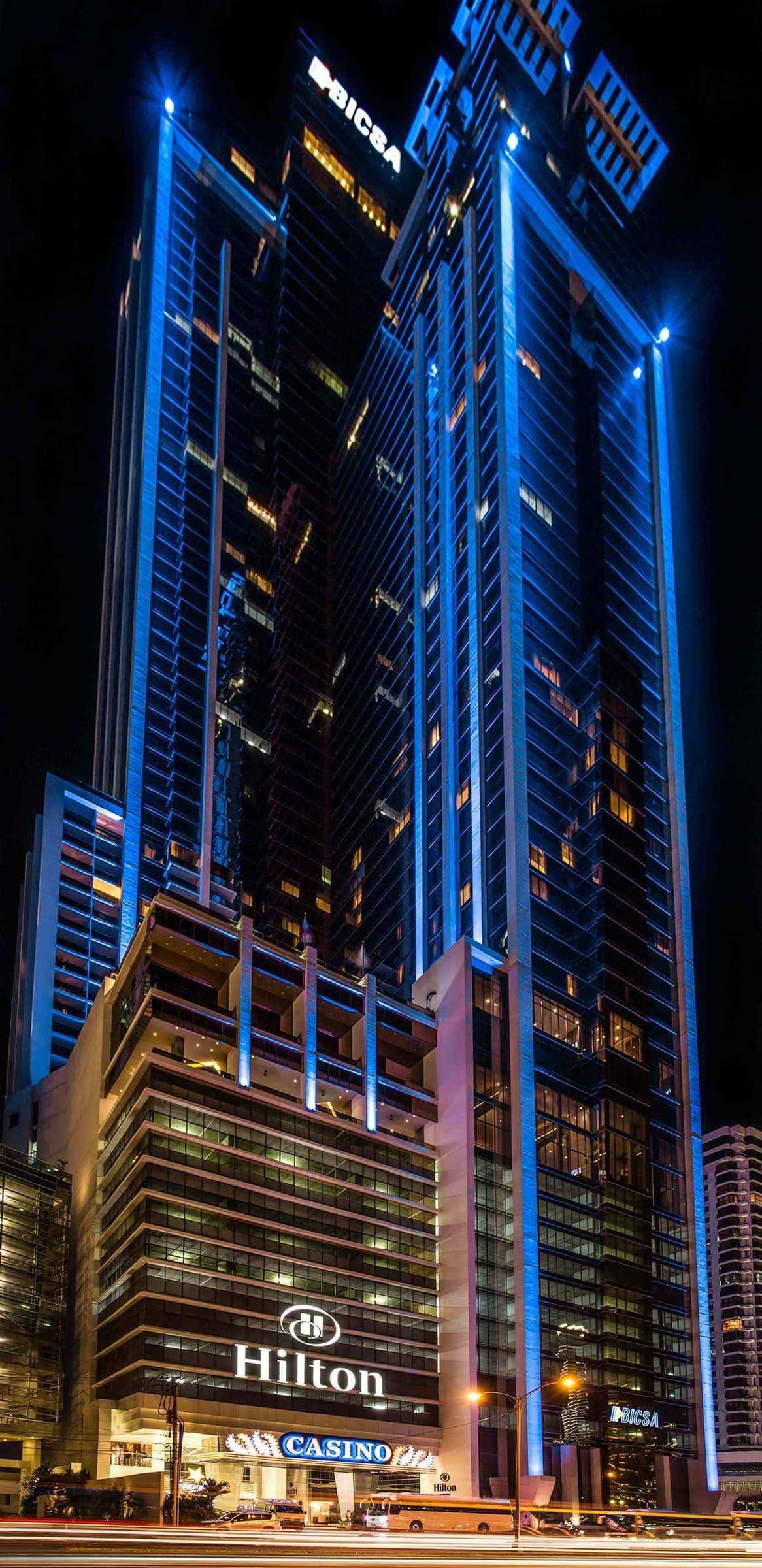 BICSA Financial Center tower lit in blue at night above the Hilton Panama entrance