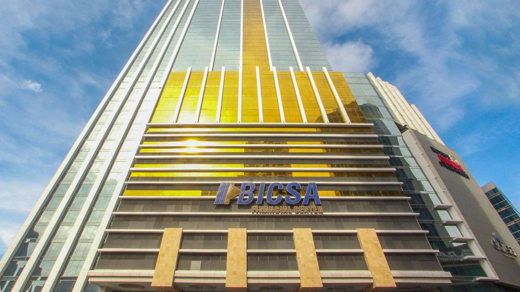 BICSA Financial Center podium and gold-striped facade seen from below with the BICSA sign
