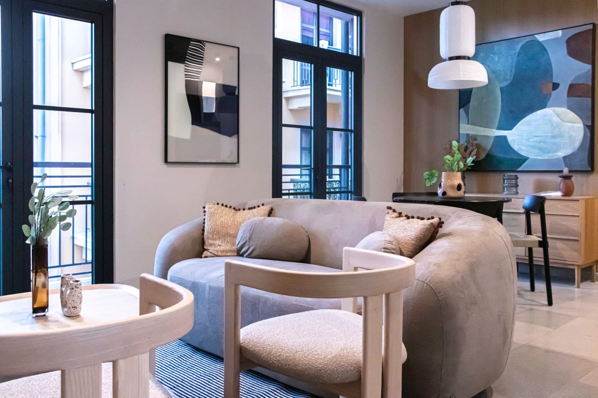 Living room with a curved sofa and French windows in a La Quince apartment