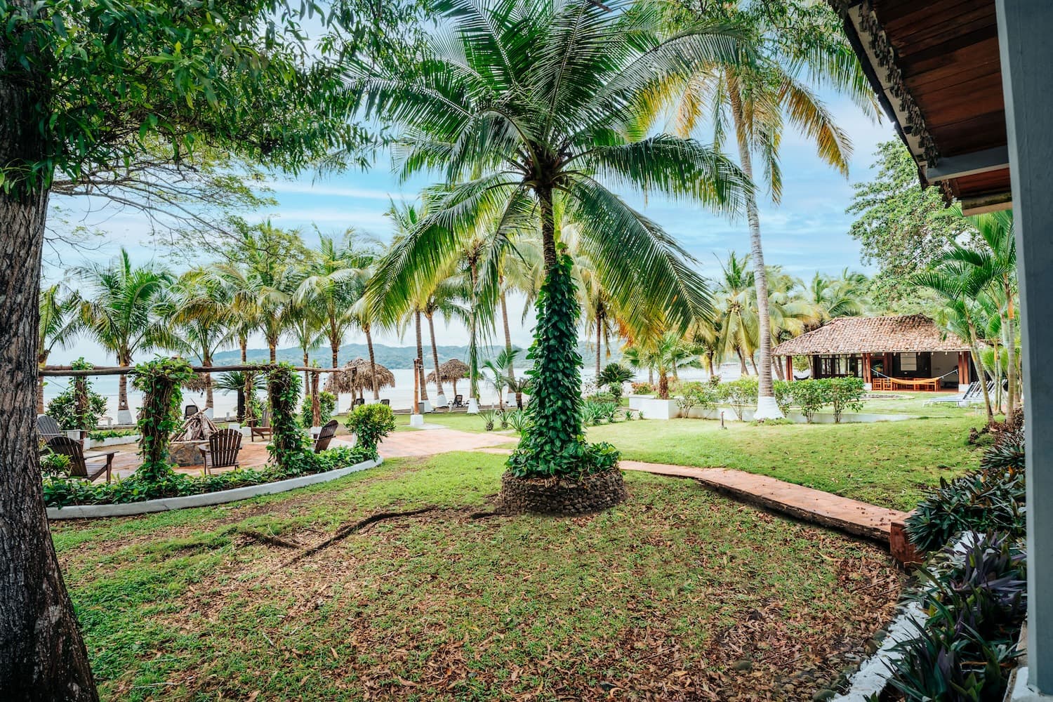 Palm-shaded lawn and thatched palapa facing the sea at Villa Marina, Playa Venao