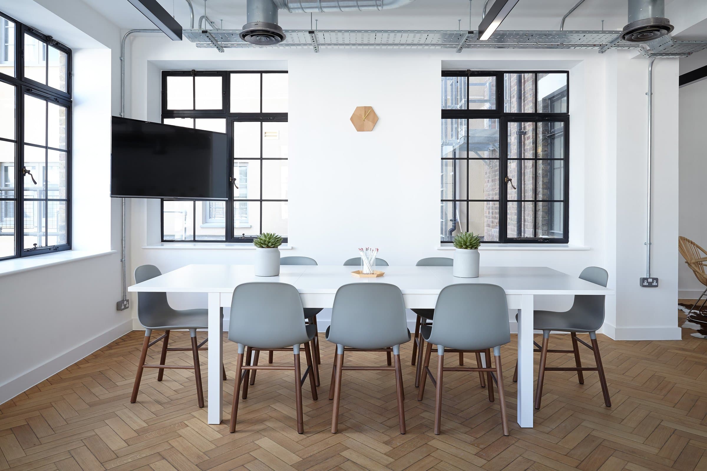Business center meeting room with a long white table, gray chairs and black-framed windows