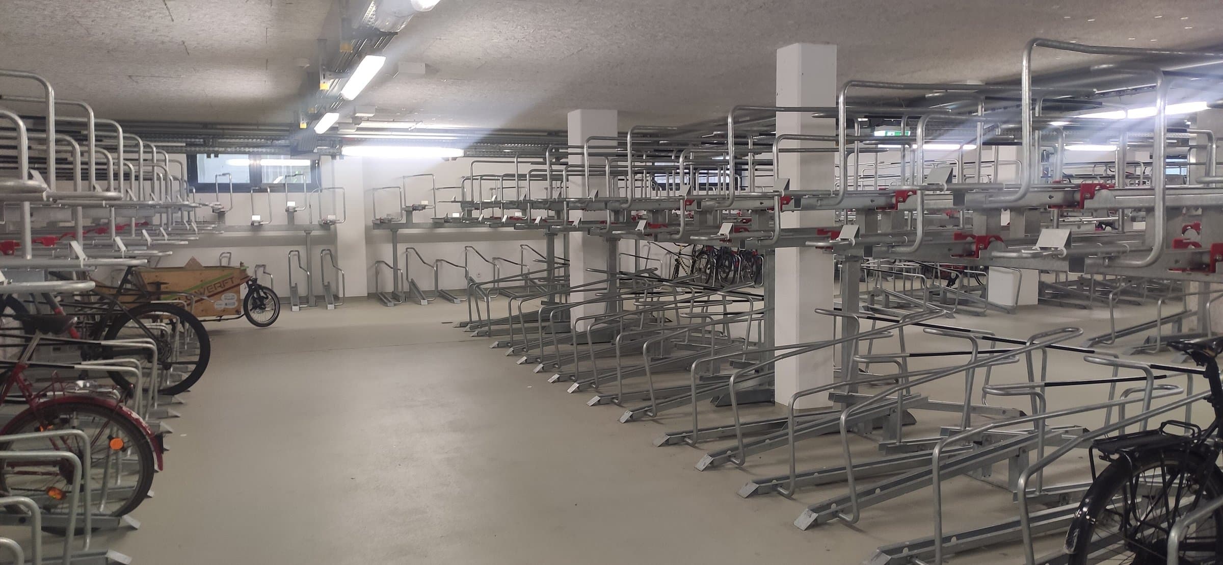 Indoor bike garage with rows of two-tier steel racks and a few parked bicycles
