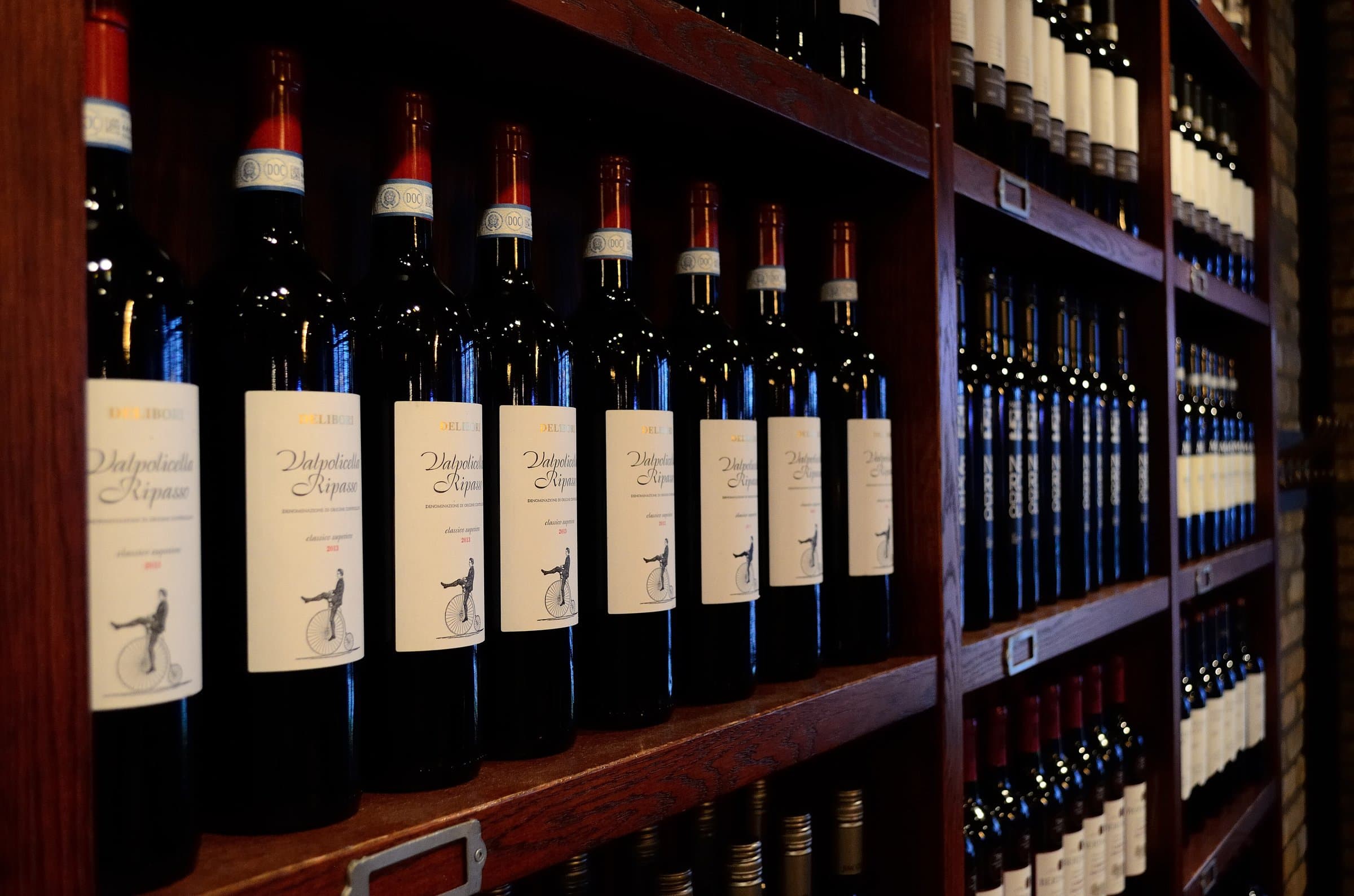 Wine bottles lined up on dark wooden shelves in a private collection