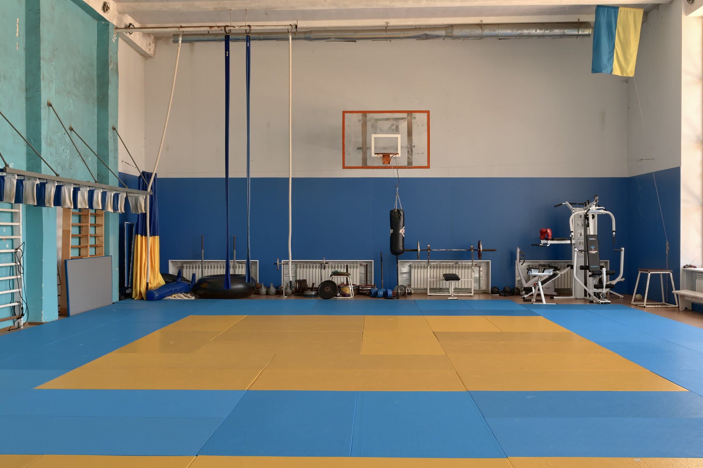 Training hall with a hanging heavy bag, a weight machine and padded floor mats