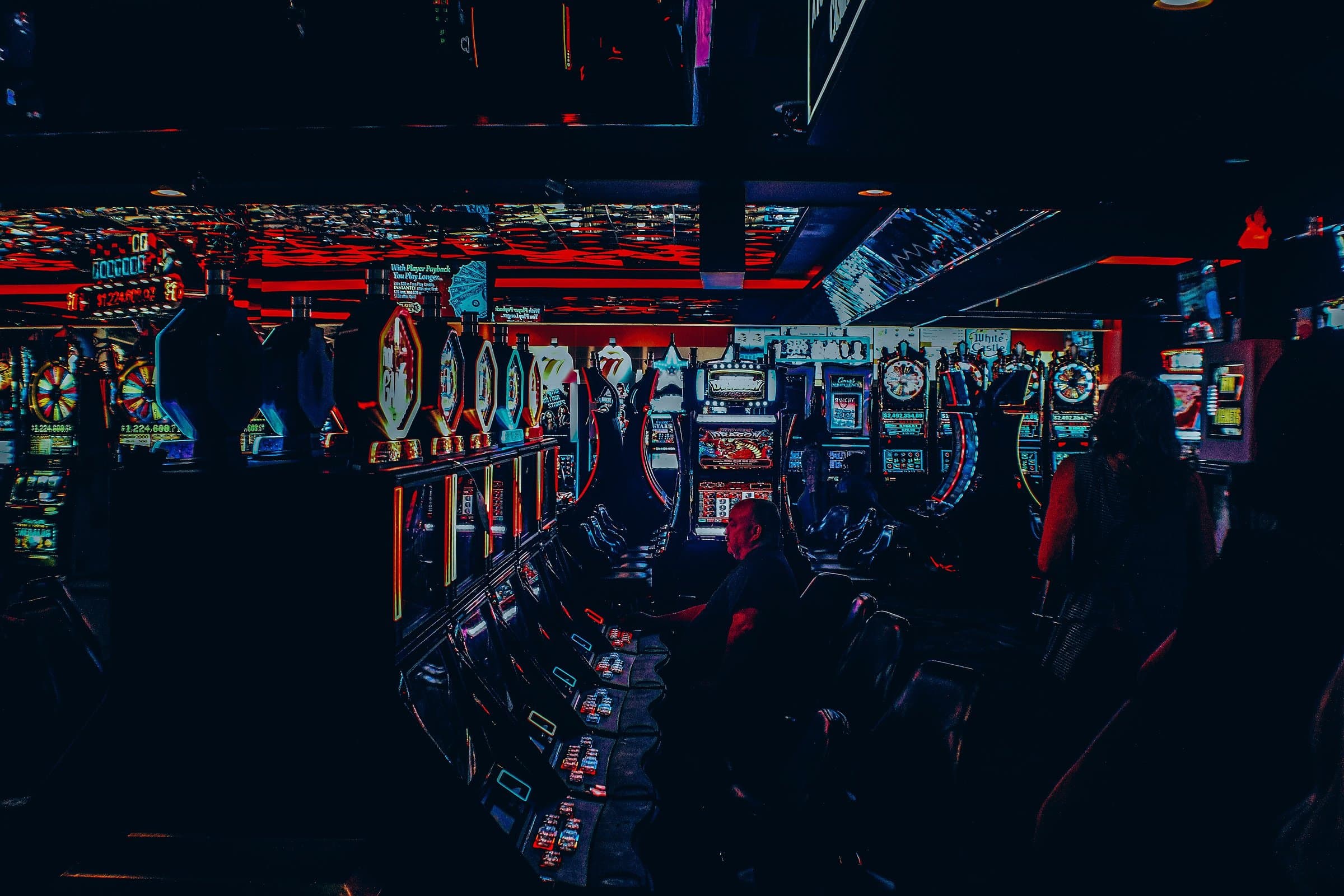 Rows of slot machines glowing with neon light in a dark casino hall