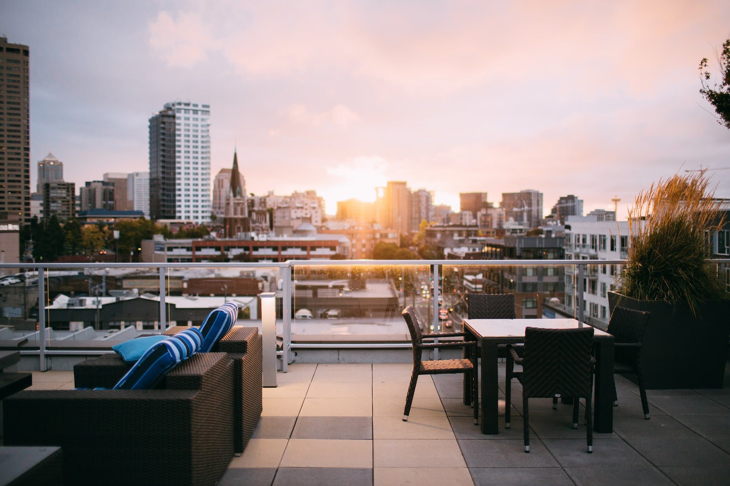Rooftop terrace with outdoor seating overlooking a city skyline at sunset
