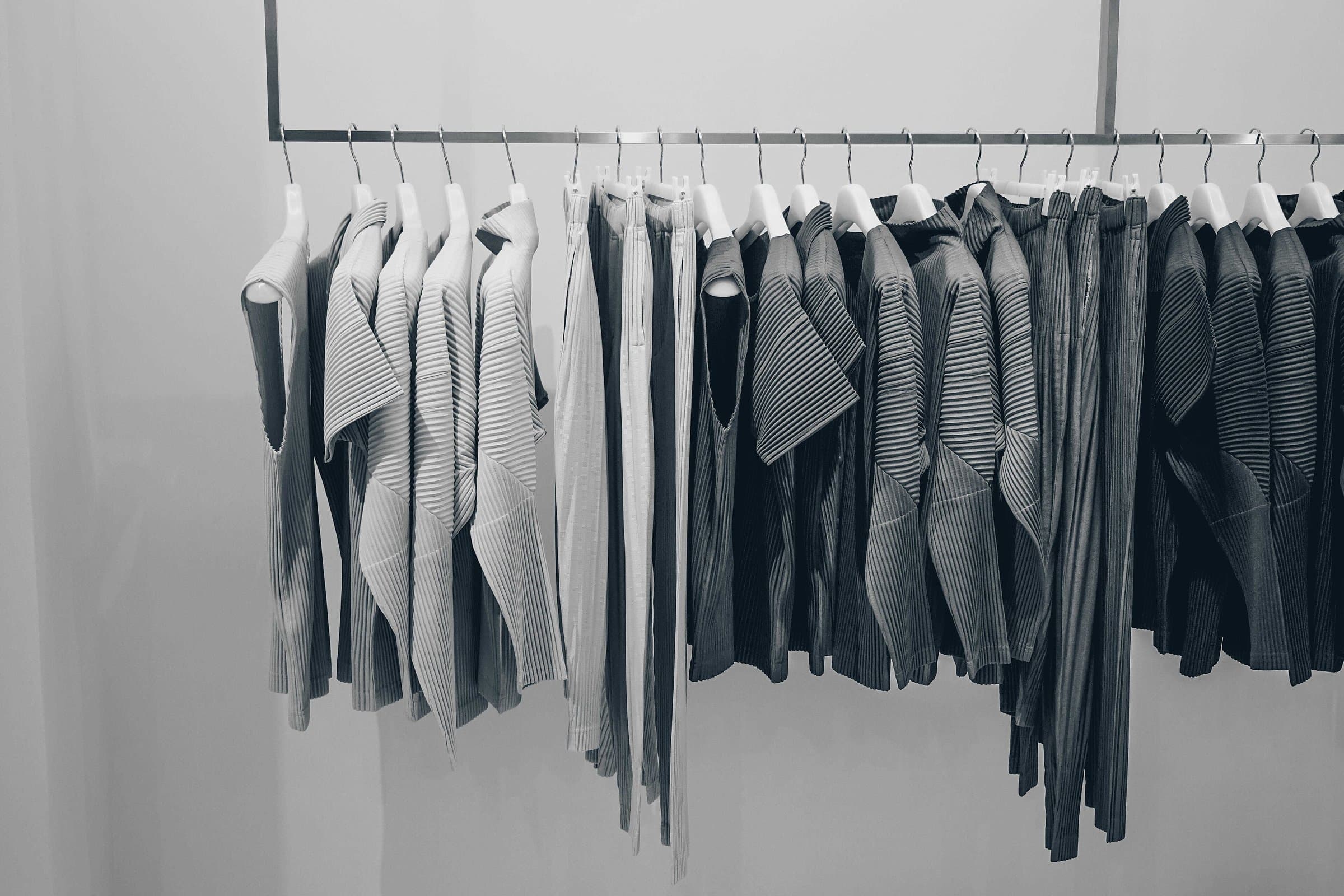 Garments in neutral tones hanging in a neat row on a wardrobe rail